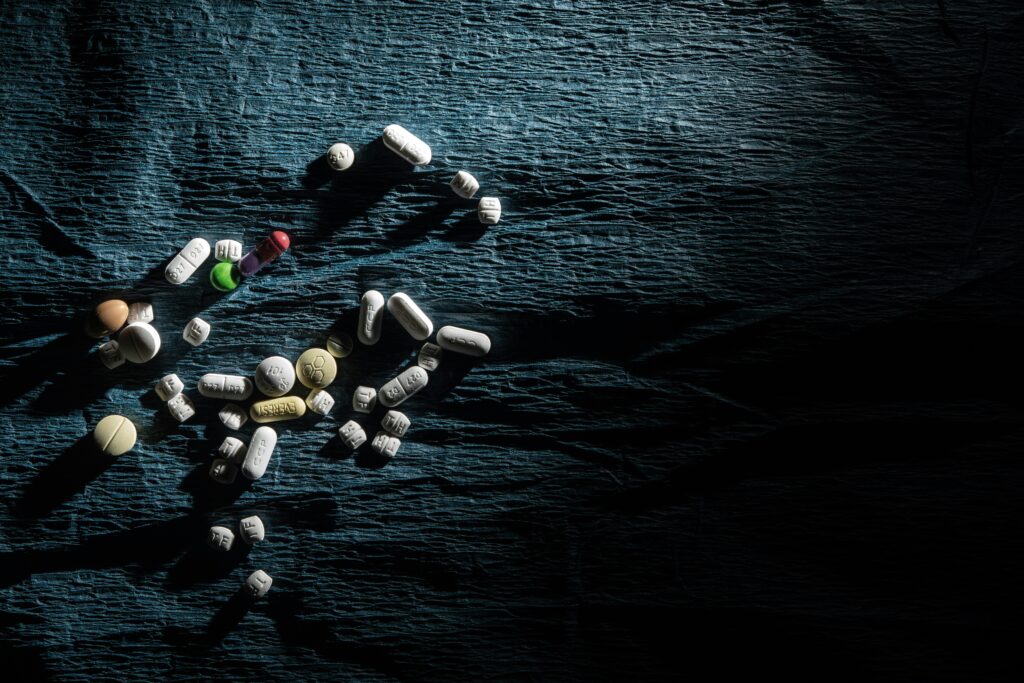Assorted pills and capsules scattered on a dark textured cloth