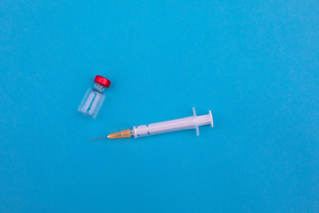 Syringe and small glass vial on a blue background