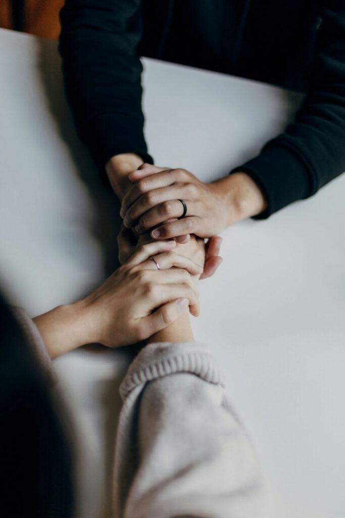 Two pairs of hands clasping each other in a show of support through mental health recovery