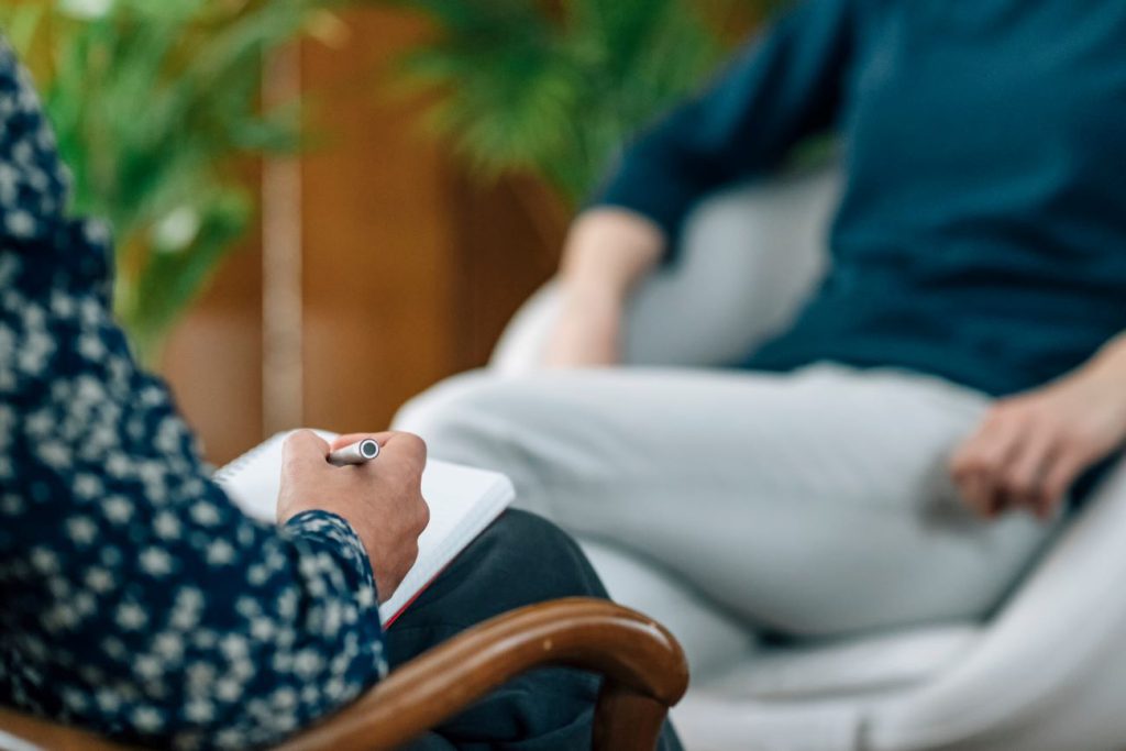 A woman taking notes on a patient during an individual therapy session in New Jersey